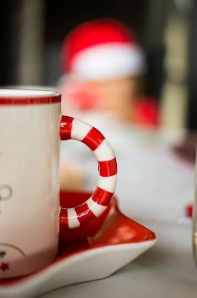 Ön planda Noel Baba gibi giyinmiş bir çocuğun olduğu bir Noel bardağının ayrıntıları.