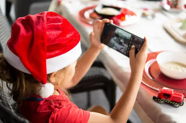 Küçük kız Noel Baba 'nın akıllı telefonuyla fotoğrafını çekiyor.