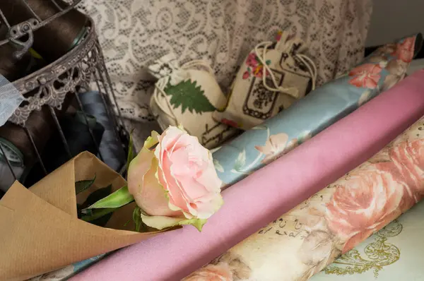 Kesim ve dikiş masasında pembe bir gülün seçici odak noktası, romantizm kavramı.