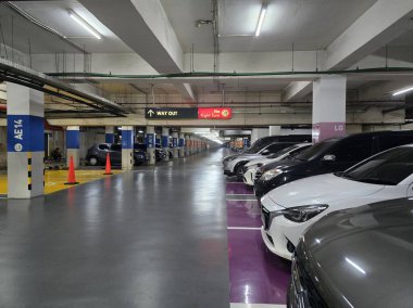 Jakarta, Endonezya - 5 Şubat 2025: hizalı arabaları, parlak ışıklandırması ve işaretli bölgeleri olan bir yeraltı otoparkı. 'Çıkış Yolu' ve 'Sağa Dönüş Yok' sürücüleri için işaretler