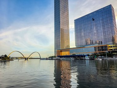 Perth, Avustralya 16 Haziran 2025: Günbatımında Elizabeth Quay rıhtımındaki modern binaların ve yaya köprüsünün yansımaları.