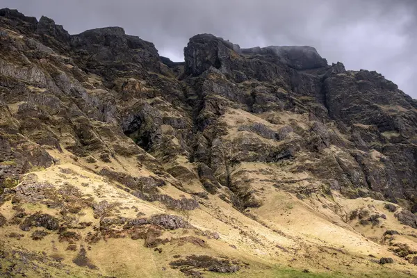 Katmanlı kaya katmanı ve canlı yeşil yosunlarla dağlık bir uçurumun çekilmesi bölgenin dramatik jeolojik tarihini vurguluyor. Jeoloji, seyahat ve doğa ile ilgili konular için ideal.