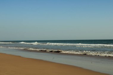 Berrak Mavi Gökyüzü Altında Yumuşak Okyanus Dalgalarıyla Huzurlu Kumsal