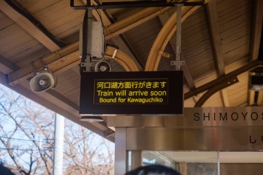 Fujiyoshida, Japonya - 10 Aralık 2023: Kawaguchiko 'ya giden bir güzergahın kalkış bilgilerini gösteren bir Shimoyoshida istasyonunun ayrıntılı bir resmi, seyahat atmosferi ve ulaşım altyapısının modernliğini vurguluyor.