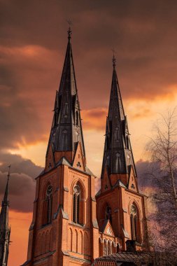Domkyrkan Uppsala İkiz Kuleleri - Uppsala Katedrali ikiz Gotik kulelerini sergileyerek altın gün batımı ışığında ele geçirildi. Parlak gökyüzü ve zamansız mimari tarafından çerçevelenmiş görkemli ve simgesel bir İskandinav simgesi..