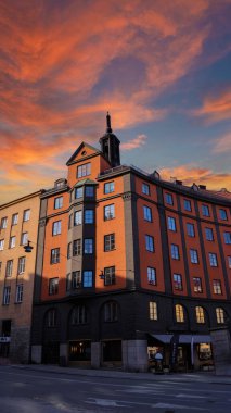 Stockholm 'deki Charming Binası - Avrupa tarzı büyüleyici bir konut binası altın saat ışığında yıkanmış, arkasında dramatik bir gökyüzü var. Sıcak renkler mimari çizgileri ve şehir cazibesini arttırır.