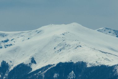 Karlı Dağ Zirvesi - Karla kaplı görkemli bir dağ zirvesinin detaylı görüntüsü yumuşak gün ışığı altında görünen tepeler ve gölgeler dramatik ve sakin bir alp manzarası yaratıyor.