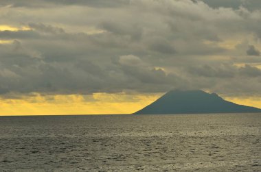 Bulutlu öğleden sonra atmosferi Manado Dağı 'nın batımını kaplıyor.