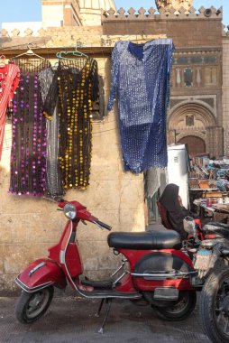 Meşgul bir cadde pazarında park etmiş havalı bir kırmızı scooter ünlü Khan el Khalili Çarşısı yakınlarında renkli kadın elbiseleri satıyor, tarihi Kahire, Mısır. 