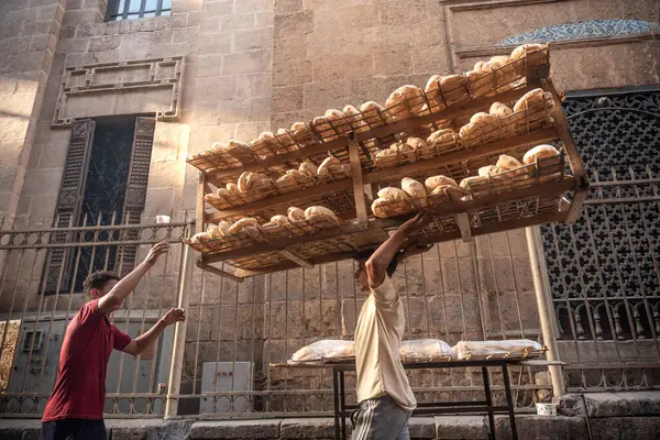 Kahire, Mısır. 3 Temmuz 2024. Mısır mutfağının temel taşlarından biri olan İslam Kahire 'nin El Hüseyin bölgesindeki bir sokak tezgahına bisikletle taze pişmiş Baladi ekmeği götürülüyor.. 