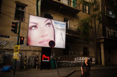  Beyrut, Lübnan. 29 Mayıs 2012. Lübnanlı yaşlı bir kadın, Lübnan 'ın Beyrut kentindeki kozmopolit güzellik ürünleri için bir reklam afişinin önünden geçiyor.. 
