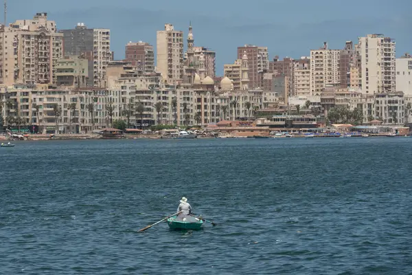 Akdeniz 'de küçük bir teknede avlanan yalnız bir Mısırlı balıkçı. Arka planda İskenderiye ufuk çizgisi olan Mısır' ın en büyük ikinci şehri.. 