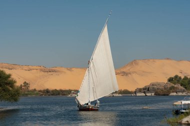 Aswan, Mısır. 10 Aralık 2022. Mısırlı Felucca yelkenli teknesinin Fil Adası 'ndaki Nil Nehri boyunca uzanan manzarası. Yukarı Mısır' daki bir Nubian Köyü.. 