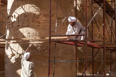 Luxor, Mısır. 12 Aralık 2022 Yerel Mısırlı işçiler Nil, Luxor, Yukarı Mısır yakınlarındaki Karnak Tapınağı 'nın antik sütunlarını temizleyip restore ediyorlar..