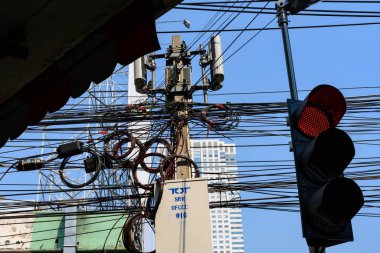 Dolaşmış kablo ve kablolarla dolu kırmızı bir trafik ışığı. Mobil iletişim direği, Bangkok şehir merkezi, Tayland..