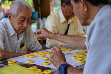 Bangkok, Tayland. 4 Mart 2025. Yaşlı adamlar bir pazar sabahı Bangkok 'taki Lumphini Park' ta Çin masa oyunu oynuyorlar..