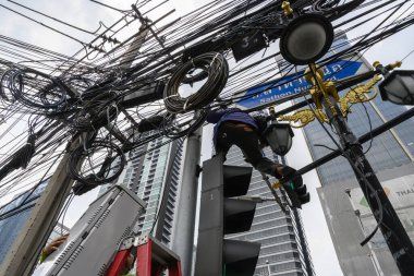 Tayland 'ın başkenti Bangkok' taki trafik ışıklarında birbirine dolanmış halat ve kablolardan oluşan bir ağ ile çalışan yerel bir Tayland mühendisi..