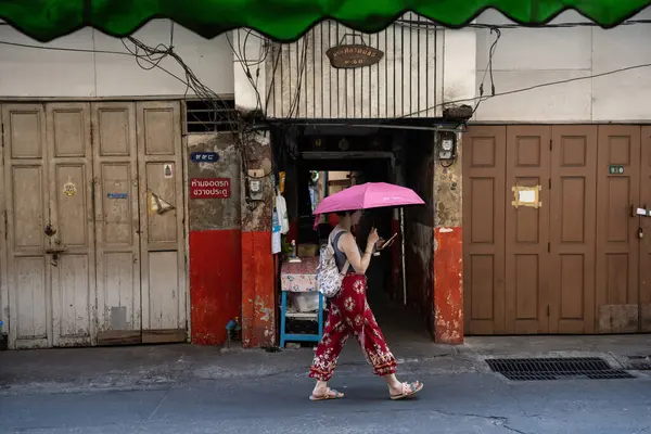 Bangkok, Tayland. 18 Mart 2025. Bir kadın, sert yaz güneşi Talat Noi Bangkok, Tayland, Asya 'dan korumak için pembe şemsiyeyle yürüyor..