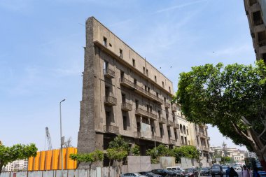 Kahire, Mısır. 15 Nisan 2025: Park halindeki araba ağaçlarının yanındaki tarihi beton bina