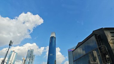 Beyaz mavi bulutlu gökdelenli, uzun, modern bir gökdelen.