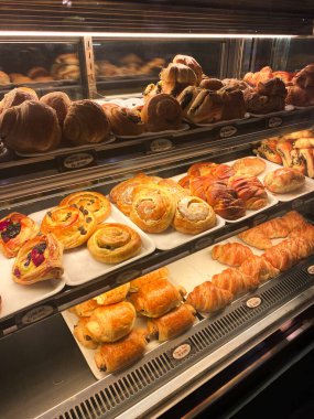 Çeşitli lezzetli fırınlanmış hamur işleri ve ekmeklerle dolu bir vitrin..