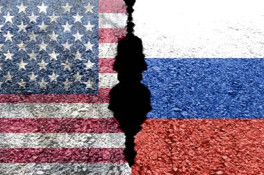 ABD ve Rus bayraklarını göstermek için ikiye bölünmüş çatlak bir duvar, iki ülke arasındaki gergin ilişkiyi simgeliyor. Jeopolitik gerilimler görsel olarak temsil edilir.