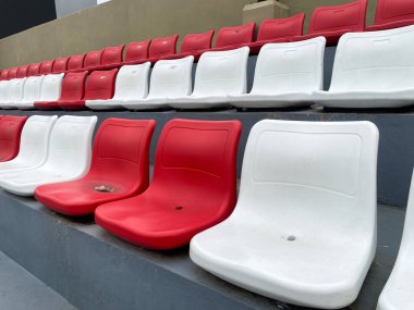Stadyumdaki boş kırmızı ve beyaz plastik koltuklar. Resim sıra sıra koltukları gösterir, bir renk ve boş alan deseni oluşturur.