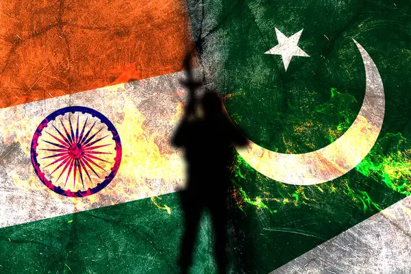 Üzüntülü Hint ve Pakistan bayrakları arasında devam eden çatışmayı simgeleyen bir siluet duruyor..