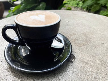 Koyu bir fincanda kalp şeklinde sanat eserleri olan enfes bir latte, sakin bir sabahta açık havada keyif alırdı. Rahatlatıcı bir kahve molası için mükemmel..