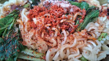 Üzerine erişte serpiştirilmiş erişte ve hardal yeşili. Çorbasız kuru erişte, olgun. Endonezya yemeği, helal.