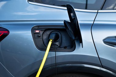 Modern elektrikli arabayı şarj etmek için bir elektrik şarj istasyonu kullanın. Ekonomik yükleme ve modern teknolojiler kavramı. 
