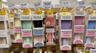 Bir mağaza rafında çeşitli Tangle Teezer saç fırçaları sergileniyor, çözme ve saç kurutma modelleri de dahil..