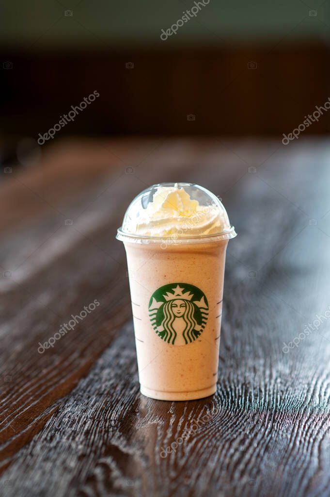 A Starbucks frappuccino-style beverage topped with whipped cream, placed on a rustic wooden surface with no people in frame.