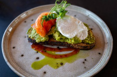 Avokado tostunun üzerine haşlanmış yumurta, füme somon, mikroyeşillik ve zanaatkar ekmeği üzerine serpiştirilmiş zeytinyağı..