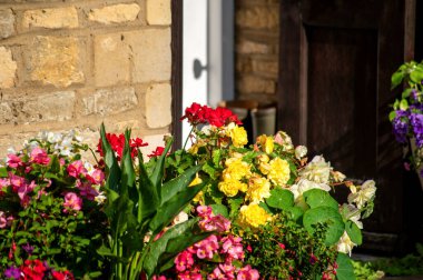 Taş bir evin girişinde çiçeklerin açtığı canlı bir düzenleme, bir yaz bahçesinin güzelliğini gözler önüne seriyor..