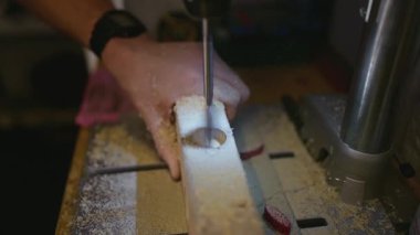 Marangozluk atölyesinde bir makineye delinen ahşap bir kalasın üst görüntüsü. Yukarıdan hassas ahşap işçiliği. Yüksek kalite 4k görüntü