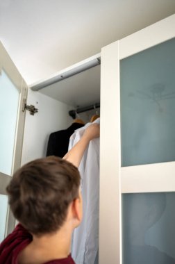 Gardıroptan okul üniforması alan bir çocuk. Konsept: okula dönüş.