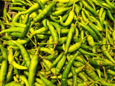 Piyasa ortamında sıralanmış doğal doku ve renkte taze yeşil biber çeşitleri. Mutfak ve yemek temalı içerik için mükemmel..