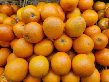 Parlak olgun portakallar bir market tezgahında dokuma sepetine yığılmıştı. Canlı turunçgiller sağlık, gıda ve üretim için idealdir..