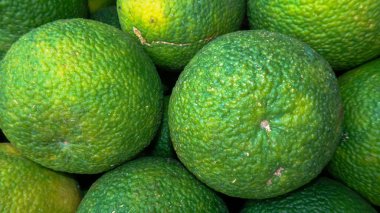 Canlı renkler, desenli kabuklar ve doğal kusurları gösteren taze yeşil portakalların yakın çekimi. Yiyecek, narenciye ve organik temalar için ideal..