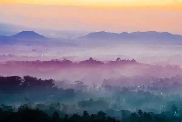Magelang, Endonezya - 13 Eylül 2024: Punthuk Setumbu 'dan Borobudur' un görkemli silueti, antik taşların altın ışıkta sisli volkanik manzaralarla birleştiği yer..