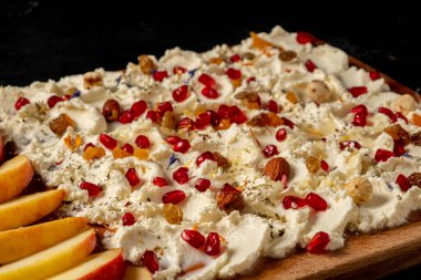 Güzel bir tereyağı tahtası. Köy süzme peyniri, fındık, kurutulmuş meyve, nar tohumu ve elma dilimleri. Sağlıklı gıda konsepti 