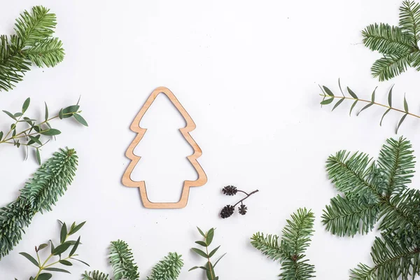 Christmas background. fir branches, Eucalyptus branches and wooden Christmas tree silhouette. Flat lay and copy space