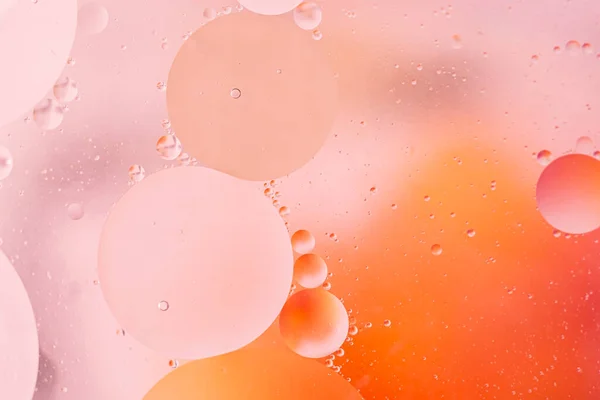 Macro drops of oil on orange surface. Delicate cosmetic background for advertising products. copy space