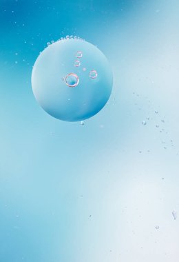 Mavi yumuşak tonlarda soyut arkaplan. Su yüzeyine makro yağ damlaları. Reklam ürünleri için hassas kozmetik arka plan. Boşluk ve gradyanı kopyala. Dikey fotoğraf