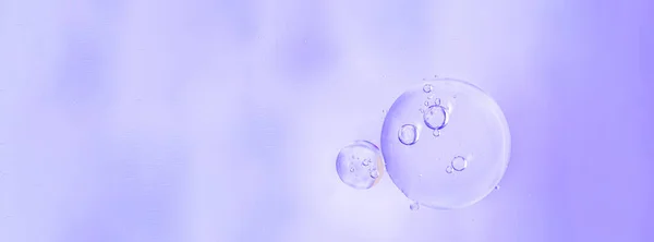 Banner. Macro drops of oil on the surface of the water. Delicate cosmetic background for promotional products in pale violet colors. copy space and gradient.