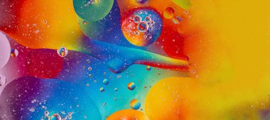 Oil drops in water and air bubbles, macro photo, selective focus. Bright multicolored rainbow background. Long banner