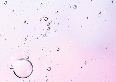 Su kabarcıkları olan yüz serumu yağı yüzeyi. Kozmetik ürünlerinin tanıtımı ve tanıtımı için soyut kozmetik sıvı yumuşak pembe arka plan. Makro fotoğraf