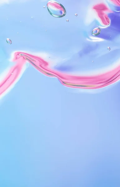 Gel texture of cosmetic products. transparent cream on a pink-blue background with bubbles. macro photo. Vertical
