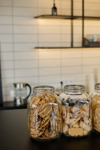Large jars of cookies on the cafe counter. Blur and selective focus. Vertical photo